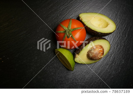 Avocado lime tomato on a black plate guacamole  Avocado lime tomato on a black plate guacamole  78637189