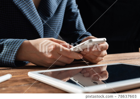 Businesswoman using mobile phone at desk 78637603