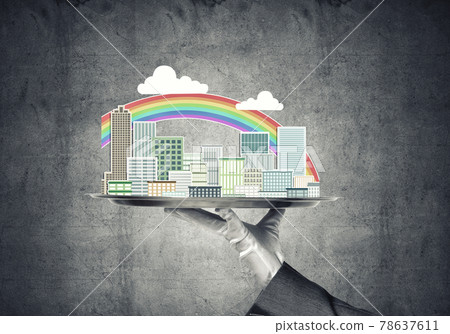 Hand holding metal tray with modern city model against concrete background Hand holding metal tray with modern city model against concrete background 78637611