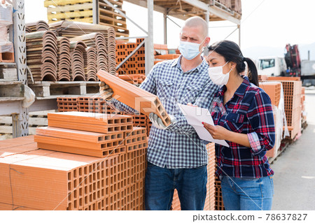 Man and woman in protective mask keep track of the number of bricks at the site of a hardware store Man and woman in protective mask keep track of the number of bricks at the site of a hardware store 78637827