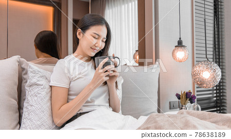 Asian woman sipping coffee on a luxurious bed in a manicured bedroom, After waking up have to drink coffee to refresh and get ready for a new day, relaxation, wake up morning, Hot coffee. Asian woman sipping coffee on a luxurious bed in a manicured bedroom, After waking up have to drink coffee to refresh and get ready for a new day, relaxation, wake up morning, Hot coffee. 78638189