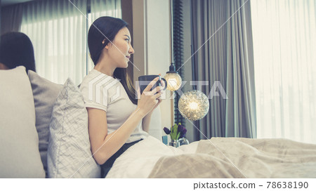 Asian woman sipping coffee on a luxurious bed in a manicured bedroom, After waking up have to drink coffee to refresh and get ready for a new day, relaxation, wake up morning, Hot coffee. Asian woman sipping coffee on a luxurious bed in a manicured bedroom, After waking up have to drink coffee to refresh and get ready for a new day, relaxation, wake up morning, Hot coffee. 78638190