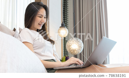 Asian woman uses laptop on bed in modern bedroom at home after she wakes up in the morning, Entertaining or relaxing using laptop technology, Wake-up activities, Happy lifestyle. Asian woman uses laptop on bed in modern bedroom at home after she wakes up in the morning, Entertaining or relaxing using laptop technology, Wake-up activities, Happy lifestyle. 78638191