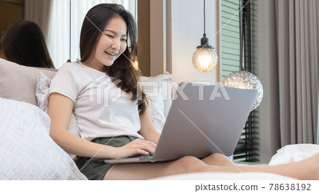 Asian woman uses laptop on bed in modern bedroom at home after she wakes up in the morning, Entertaining or relaxing using laptop technology, Wake-up activities, Happy lifestyle. Asian woman uses laptop on bed in modern bedroom at home after she wakes up in the morning, Entertaining or relaxing using laptop technology, Wake-up activities, Happy lifestyle. 78638192