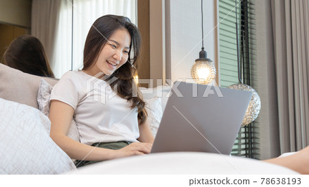 Asian woman uses laptop on bed in modern bedroom at home after she wakes up in the morning, Entertaining or relaxing using laptop technology, Wake-up activities, Happy lifestyle. Asian woman uses laptop on bed in modern bedroom at home after she wakes up in the morning, Entertaining or relaxing using laptop technology, Wake-up activities, Happy lifestyle. 78638193