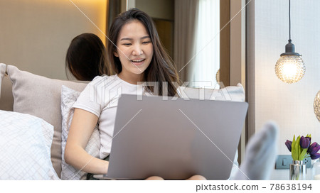 Asian woman uses laptop on bed in modern bedroom at home after she wakes up in the morning, Entertaining or relaxing using laptop technology, Wake-up activities, Happy lifestyle. Asian woman uses laptop on bed in modern bedroom at home after she wakes up in the morning, Entertaining or relaxing using laptop technology, Wake-up activities, Happy lifestyle. 78638194