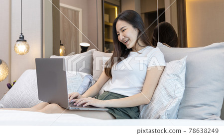 Asian woman uses laptop on bed in modern bedroom at home after she wakes up in the morning, Entertaining or relaxing using laptop technology, Wake-up activities, Happy lifestyle. Asian woman uses laptop on bed in modern bedroom at home after she wakes up in the morning, Entertaining or relaxing using laptop technology, Wake-up activities, Happy lifestyle. 78638249
