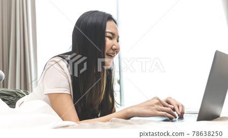 Asian woman uses laptop on bed in modern bedroom at home after she wakes up in the morning, Entertaining or relaxing using laptop technology, Wake-up activities, Happy lifestyle. Asian woman uses laptop on bed in modern bedroom at home after she wakes up in the morning, Entertaining or relaxing using laptop technology, Wake-up activities, Happy lifestyle. 78638250