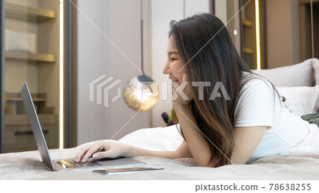 Asian woman uses laptop on bed in modern bedroom at home after she wakes up in the morning, Entertaining or relaxing using laptop technology, Wake-up activities, Happy lifestyle. Asian woman uses laptop on bed in modern bedroom at home after she wakes up in the morning, Entertaining or relaxing using laptop technology, Wake-up activities, Happy lifestyle. 78638255