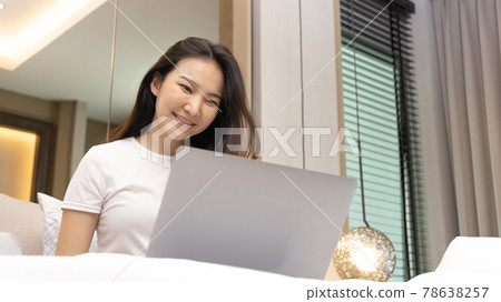 Asian woman uses laptop on bed in modern bedroom at home after she wakes up in the morning, Entertaining or relaxing using laptop technology, Wake-up activities, Happy lifestyle. Asian woman uses laptop on bed in modern bedroom at home after she wakes up in the morning, Entertaining or relaxing using laptop technology, Wake-up activities, Happy lifestyle. 78638257