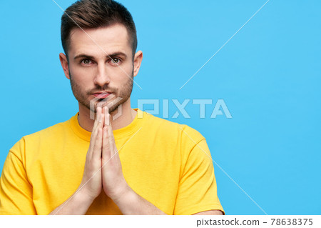 Portrait of handsome man with praying hands looking to camera with copy space 78638375