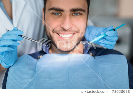 Closeup of handsome young man showing his white teeth Closeup of handsome young man showing his white teeth 78638658
