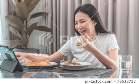 Asian woman eating fresh salad and using tablet at her home dining table, Vegetable salads are rich in vitamins and minerals, Fat-low-calorie and high-fiber diets, Healthy food, Appetizer. Asian woman eating fresh salad and using tablet at her home dining table, Vegetable salads are rich in vitamins and minerals, Fat-low-calorie and high-fiber diets, Healthy food, Appetizer. 78638788