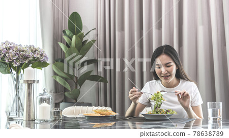 Asian woman eating salad on the dining table smiling and happy, Vegetable salads are rich in vitamins and minerals, Fat-low-calorie and high-fiber diets, Health care by eating fresh vegetables. 78638789