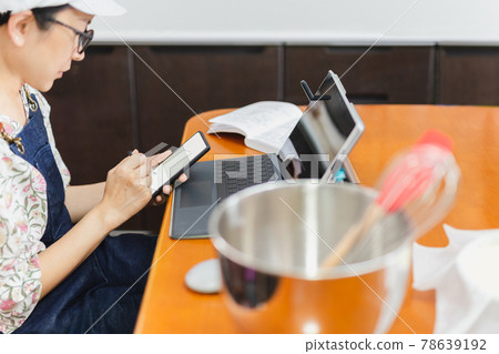 Businesswoman baker working on mobile phone with laptop on table. 78639192