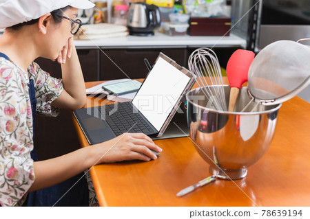 Businesswoman baker working on laptop with bakery equipment on table. Businesswoman baker working on laptop with bakery equipment on table. 78639194