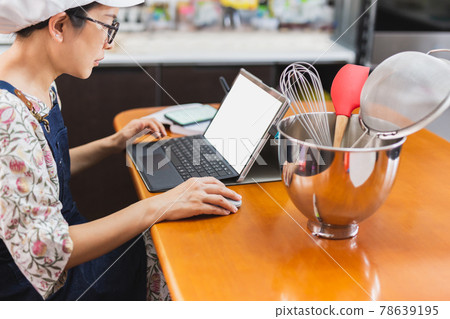 Businesswoman baker working on with laptop bakery equipment on table. Businesswoman baker working on with laptop bakery equipment on table. 78639195