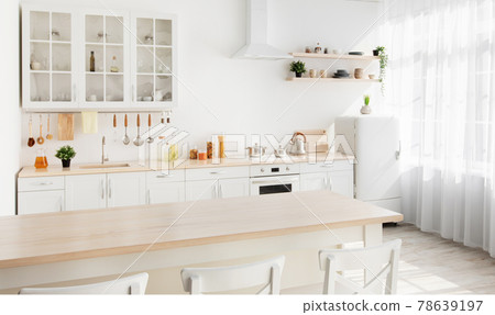 Light kitchen design with white wooden furniture and island, utensils and kitchenware on shelves, range hood 78639197
