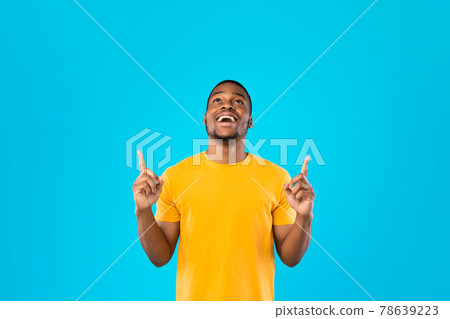 African Guy Pointing Fingers Up Looking Upward Over Blue Background 78639223