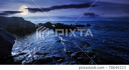 sea coast scenery at night. boulders in the calm water. few clouds on the sky in full moon light. lonely place for summer vacations. sunny weather 78640323