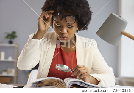 Surprised business woman takes off glasses as she reads an amazing fact in a book 78640336