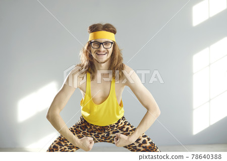 Happy skinny man in funny retro activewear smiling and showing his weak arm muscles Happy skinny man in funny retro activewear smiling and showing his weak arm muscles 78640388