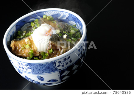 Photographed a hot yellowtail teriyaki rice bowl topped with hot balls and plenty of small onions on a black background 78640586