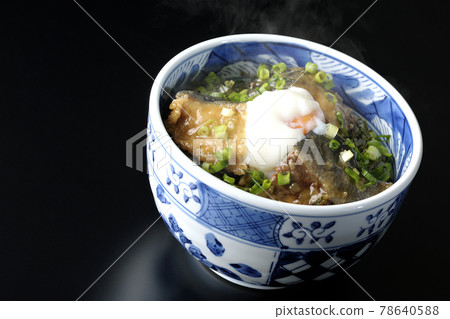 Photographed a hot yellowtail teriyaki rice bowl topped with hot balls and plenty of small onions on a black background 78640588