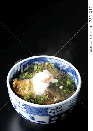 Photographed a hot yellowtail teriyaki rice bowl topped with hot balls and plenty of small onions on a black background 78640594
