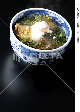 Photographed a hot yellowtail teriyaki rice bowl topped with hot balls and plenty of small onions on a black background 78640597