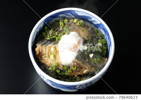 A bird's-eye view of a hot yellowtail teriyaki rice bowl topped with hot balls and plenty of small onions on a black background 78640623