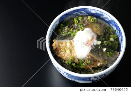 A bird's-eye view of a hot yellowtail teriyaki rice bowl topped with hot balls and plenty of small onions on a black background 78640625