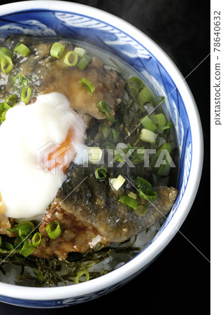 A bird's-eye view of a hot yellowtail teriyaki rice bowl topped with hot balls and plenty of small onions on a black background 78640632