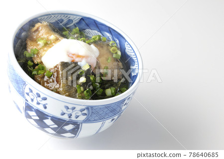 Photographed a hot yellowtail teriyaki rice bowl topped with hot balls and plenty of small onions on a white background 78640685