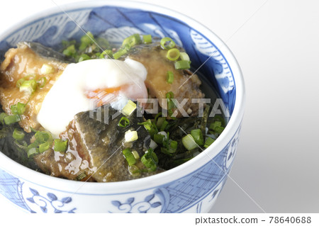 Photographed a hot yellowtail teriyaki rice bowl topped with hot balls and plenty of small onions on a white background 78640688