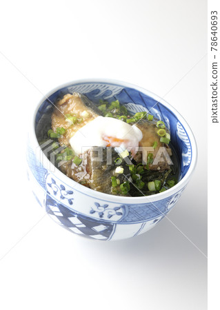 Photographed a hot yellowtail teriyaki rice bowl topped with hot balls and plenty of small onions on a white background 78640693