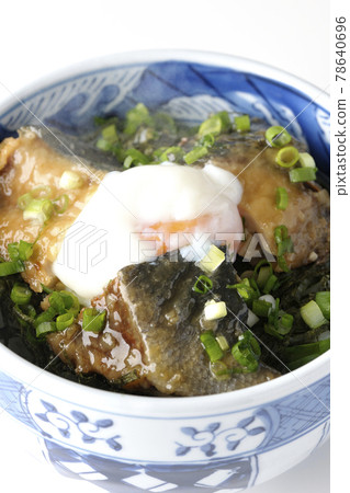 Photographed a hot yellowtail teriyaki rice bowl topped with hot balls and plenty of small onions on a white background 78640696