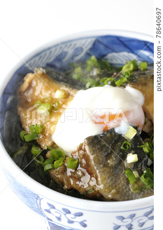 Photographed a hot yellowtail teriyaki rice bowl topped with hot balls and plenty of small onions on a white background 78640697