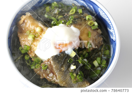 A bird's-eye view of a hot yellowtail teriyaki rice bowl topped with hot balls and plenty of small onions on a white background 78640773