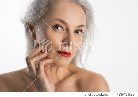 Woman with red lips looking to the camera with light smile and touching her cheek Woman with red lips looking to the camera with light smile and touching her cheek 78643638