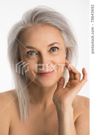 Woman with grey hair holding hands near her face and smiling 78643692