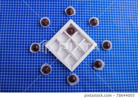 Flat lay sweet chocolate candies around the box. 78644005