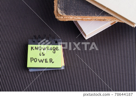 Knowledge is power concept. Small notebook with stack of books. Knowledge is power concept. Small notebook with stack of books. 78644187