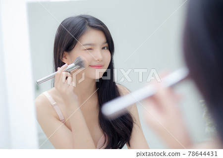 Beauty portrait young asian woman smiling with face looking mirror applying make up. 78644431