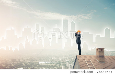 Engineer man standing on roof and looking in binoculars. Mixed m 78644673