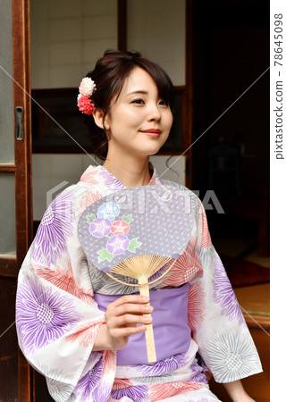 A woman wearing a yukata with a Uchiwa on the porch 78645098