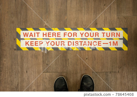 Wait your turn, keep your distance sign on a store floor. 78645408