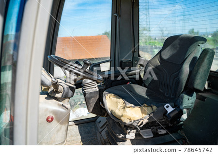 Old empty shabby driver's seat in cab of tractor, crane at a farm 78645742