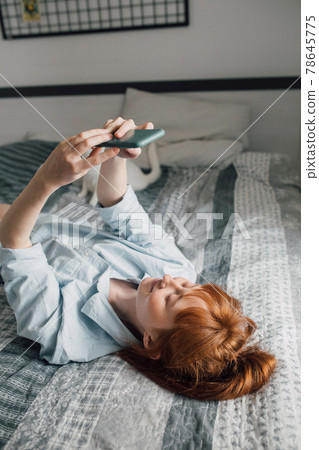 Young woman laying at the back making selfie alone at the bedroom Young woman laying at the back making selfie alone at the bedroom 78645775