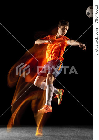 Young caucasian male football or soccer player kicking ball for the goal in mixed light on dark background. Concept of healthy lifestyle, professional sport, hobby. 78646013